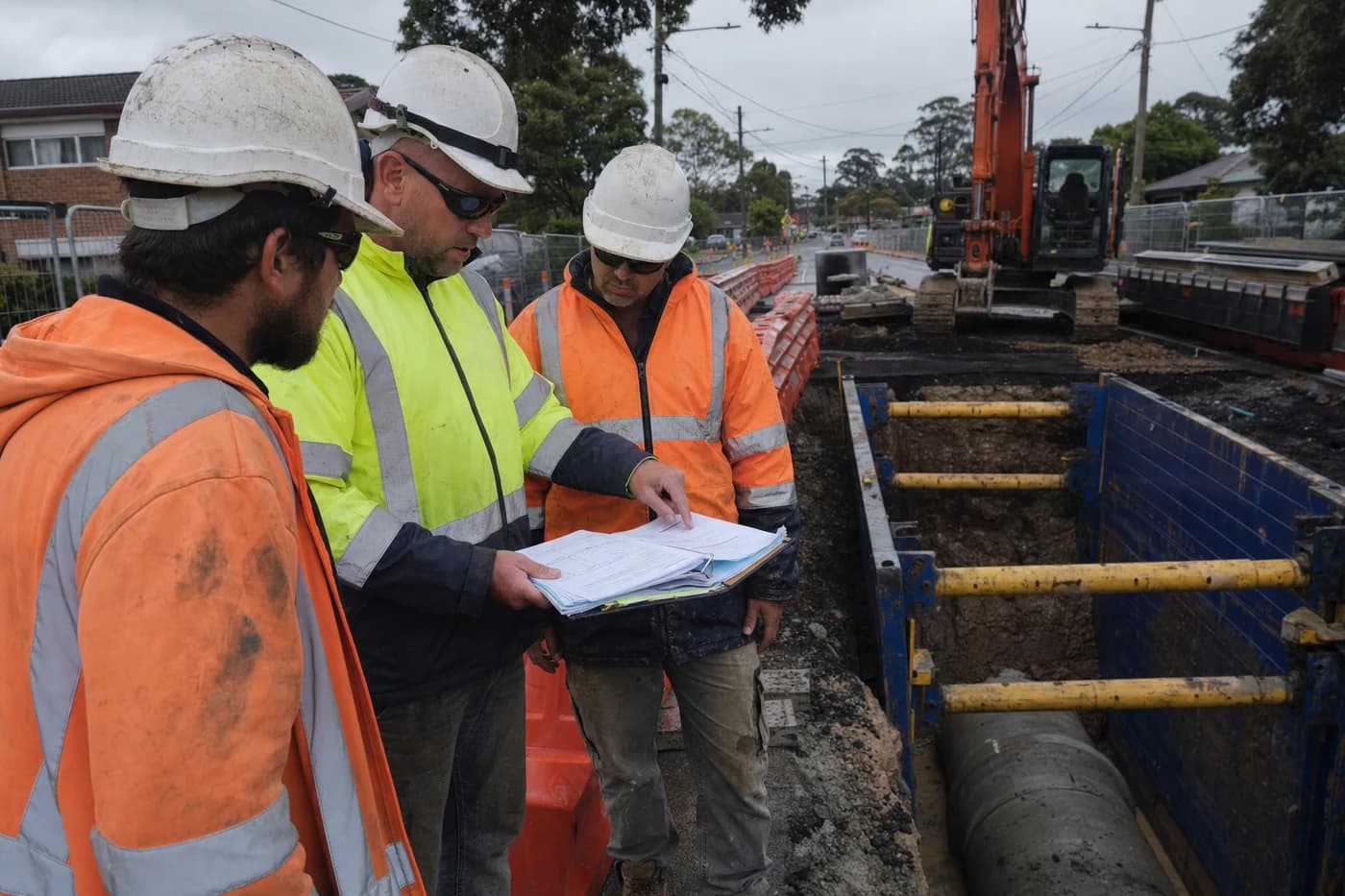 Supervisor reviewing traffic management and excavation safety plan with crew at live road stormwater works site in Sydney